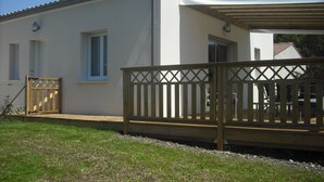 Ein zweistöckiges Gebäude mit weißer Fassade, einer Holzterrasse und einer überdachten Veranda.