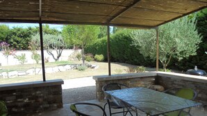 An outdoor patio with a table and chairs, stone walls, and a view of the garden. - Provence, its lavender, the song of the cicadas, the sun ... Let yourself be seduced ... (Carpentras)