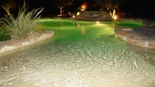 A nighttime swimming pool with clear water, surrounded by stone edges and illuminated by ambient lighting. - Provence, its lavender, the song of the cicadas, the sun ... Let yourself be seduced ... (Carpentras)