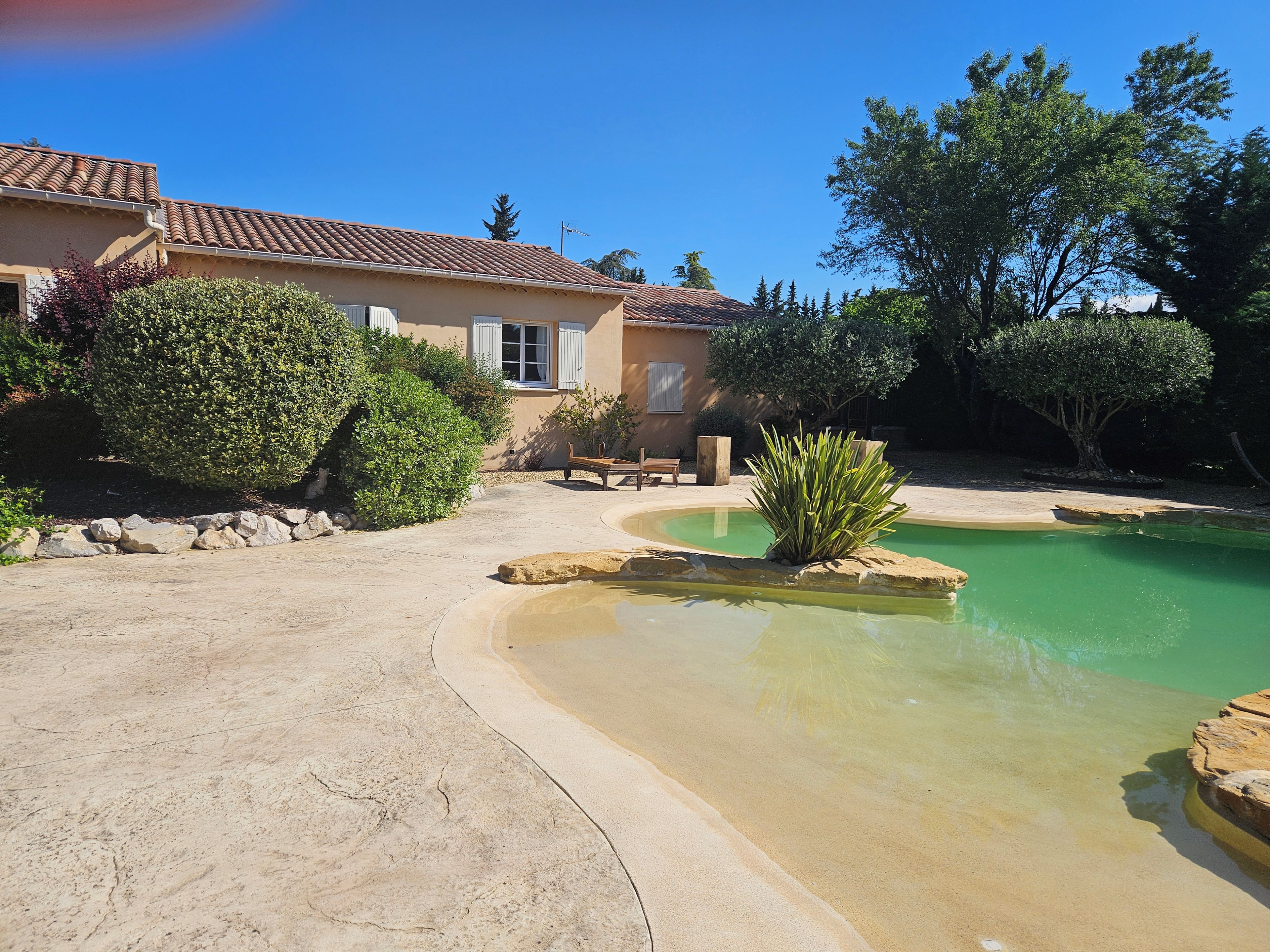 Uma casa com piscina, rodeada por vegetação e um espaço de varanda.