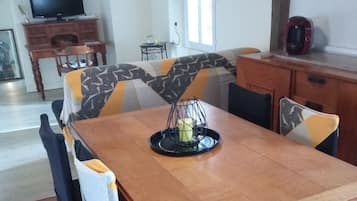 Un comedor con mesa de madera, sillas y una araña.