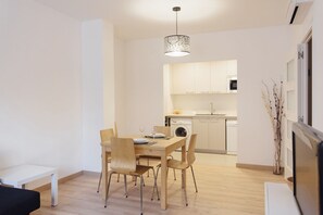 Una cucina moderna con mobili bianchi, un tavolo da pranzo con sedie e una lampada a sospensione.