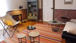 A room with a brick wall, a white door, a bookshelf, a sofa, a chair, and a small round table. - Large apartment with view in 1900 villa (Plombières-les-Bains)