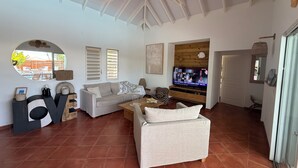 A living room with a sofa, TV, and a large mirror. - VILLA SUZANNA in the heart of Orient Bay. Beach and restaurants: 3–4 minutes on foot (baie orientale)
