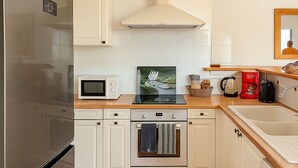 Una cuina amb armaris blancs, un refrigerador d'acer inoxidable, un microones, una cuina i un rentatall.