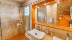 Un bany modern amb dutxa de vidre, un mirall gran i un lavabo amb rentapelats i dues aixetes.