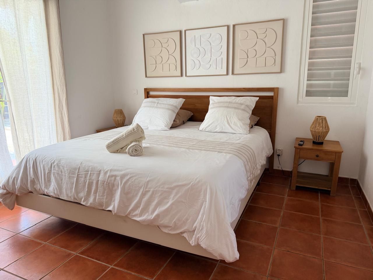 A bedroom with a bed, a nightstand, and wall art.