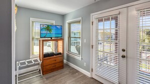 A room with a wooden entertainment unit, a TV on a stand, and a view through the window.