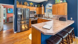 A modern kitchen with wooden cabinets, stainless steel appliances, and a large island with stools.