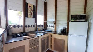 A compact kitchen with a sink, stove, and microwave. - Pretty country bungalow (Saint-Esprit)