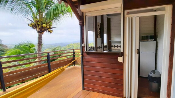 A wooden balcony with a view of lush greenery and mountains. - Pretty country bungalow (Saint-Esprit)