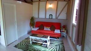 A cozy living room with a red sofa, a coffee table, and a patterned rug. - Pretty country bungalow (Saint-Esprit)