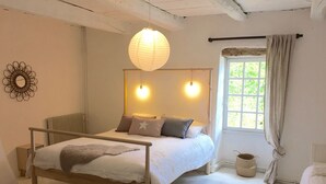 Et soveværelse med en træseng, to sengeborde med lamper, et vindue med gardiner, en radiator og en dekorativ vægdekoration.