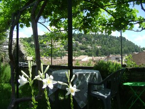 Eine Terrasse mit Tisch und Stühlen mit Blick auf ein Dorf am Hang.