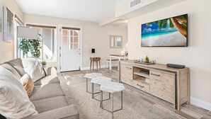 Uma sala de estar moderna com sofá, mesa de centro, televisão e um armário de madeira.