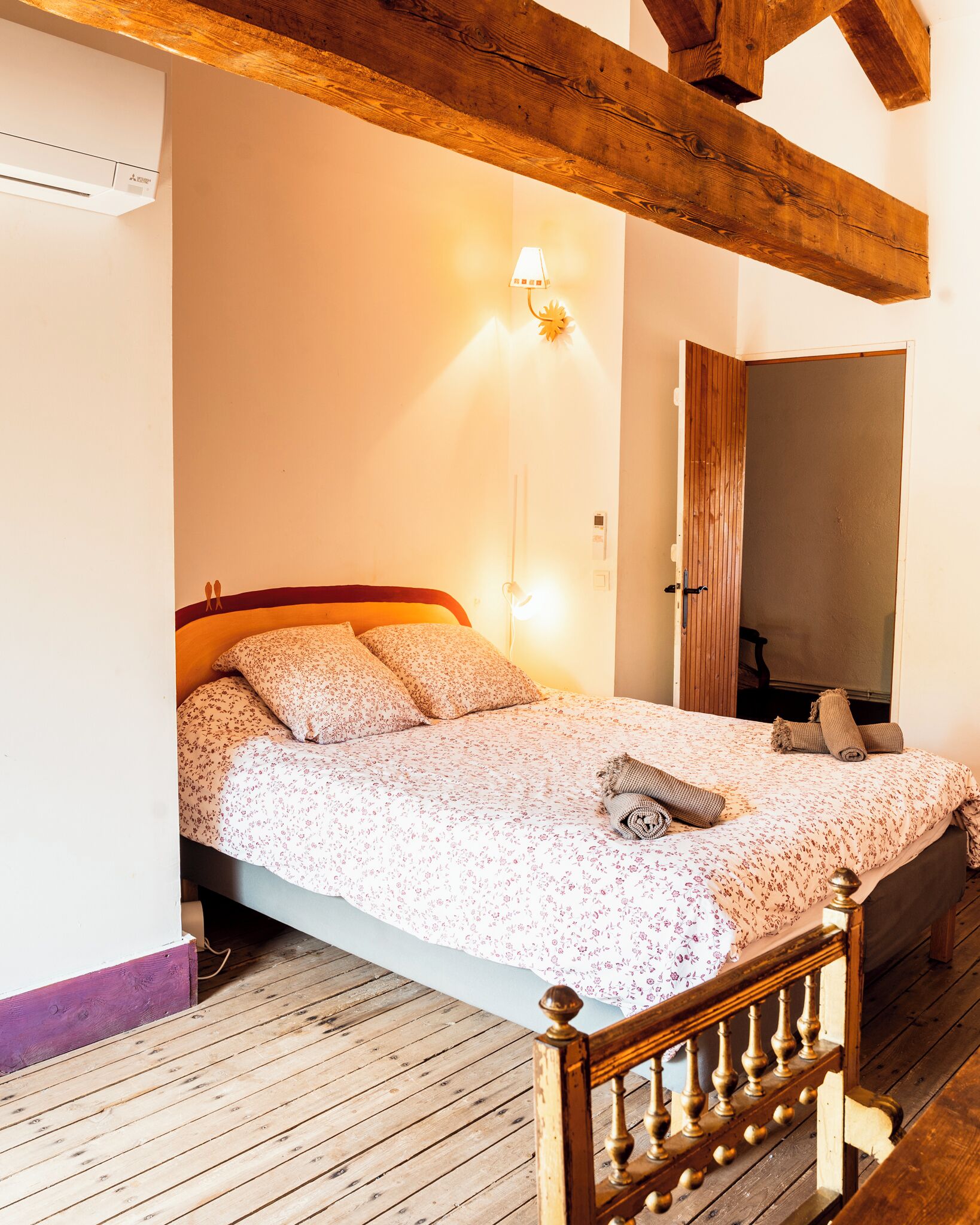 Une chambre avec un lit en bois, une lampe de chevet et un plancher en bois.