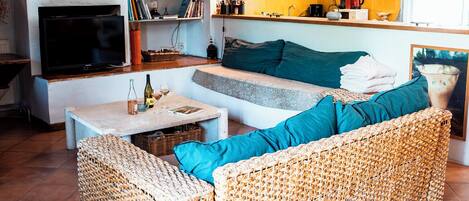 Una sala de estar acogedora con sofá, televisión y una zona de cocina con estufa y fregadero.