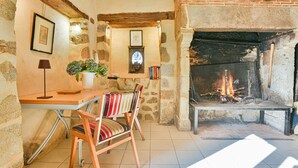 A rustic stone room with a fireplace, a wooden table, a chair, and a lamp. - Maison de Caractère with swimming pool Unbeatable view (Saint-Victurnien)