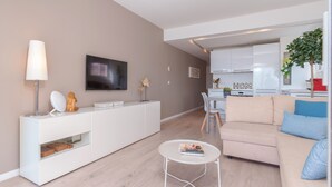 A modern living room with a sofa, coffee table, and a flat-screen TV mounted on the wall. - Want to GET AWAY from it all by the sea in GOLFE JUAN? (Vallauris)