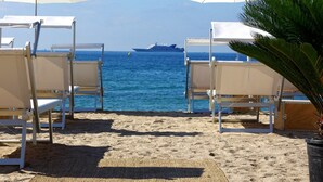 A beach with rows of white sun loungers and a large ship in the background. - Want to GET AWAY from it all by the sea in GOLFE JUAN? (Vallauris)