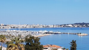 A marina with boats, a coastal cityscape, and palm trees. - Want to GET AWAY from it all by the sea in GOLFE JUAN? (Vallauris)