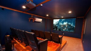 Ein Heimkinozimmer mit einer großen Leinwand, bequemen Sitzgelegenheiten und einem Projektor.