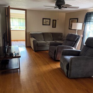 A living room with a sofa, a recliner, a TV stand, and a ceiling fan. - GRANDMA'S GET-A-WAY (Water Front property ) WIFI. Private covered one bay dock. (Warsaw)