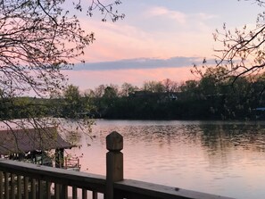 A tranquil lakeside view with a wooden deck and a gazebo.