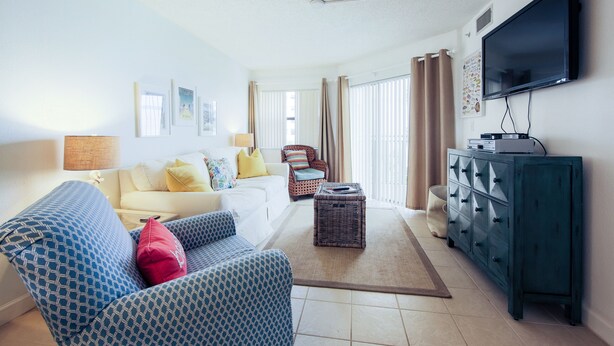 A living room with a sofa, armchairs, a coffee table, a TV, and a cabinet.