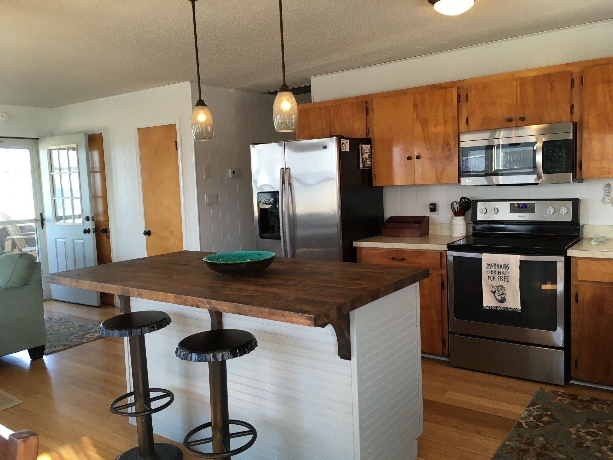 A kitchen with wooden cabinets, stainless steel appliances, a bar stool area, and a refrigerator with a water dispenser.