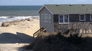 A beach house with a small porch and a view of the ocean. - SEA GLASS OCEANFRONT COTTAGE.  (Nags Head)