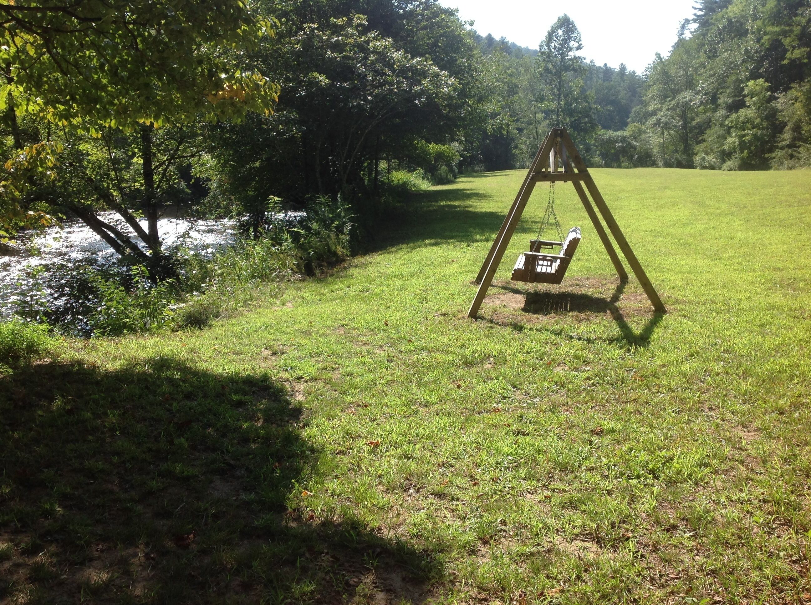 A grassy area with a wooden swing set and a bench.