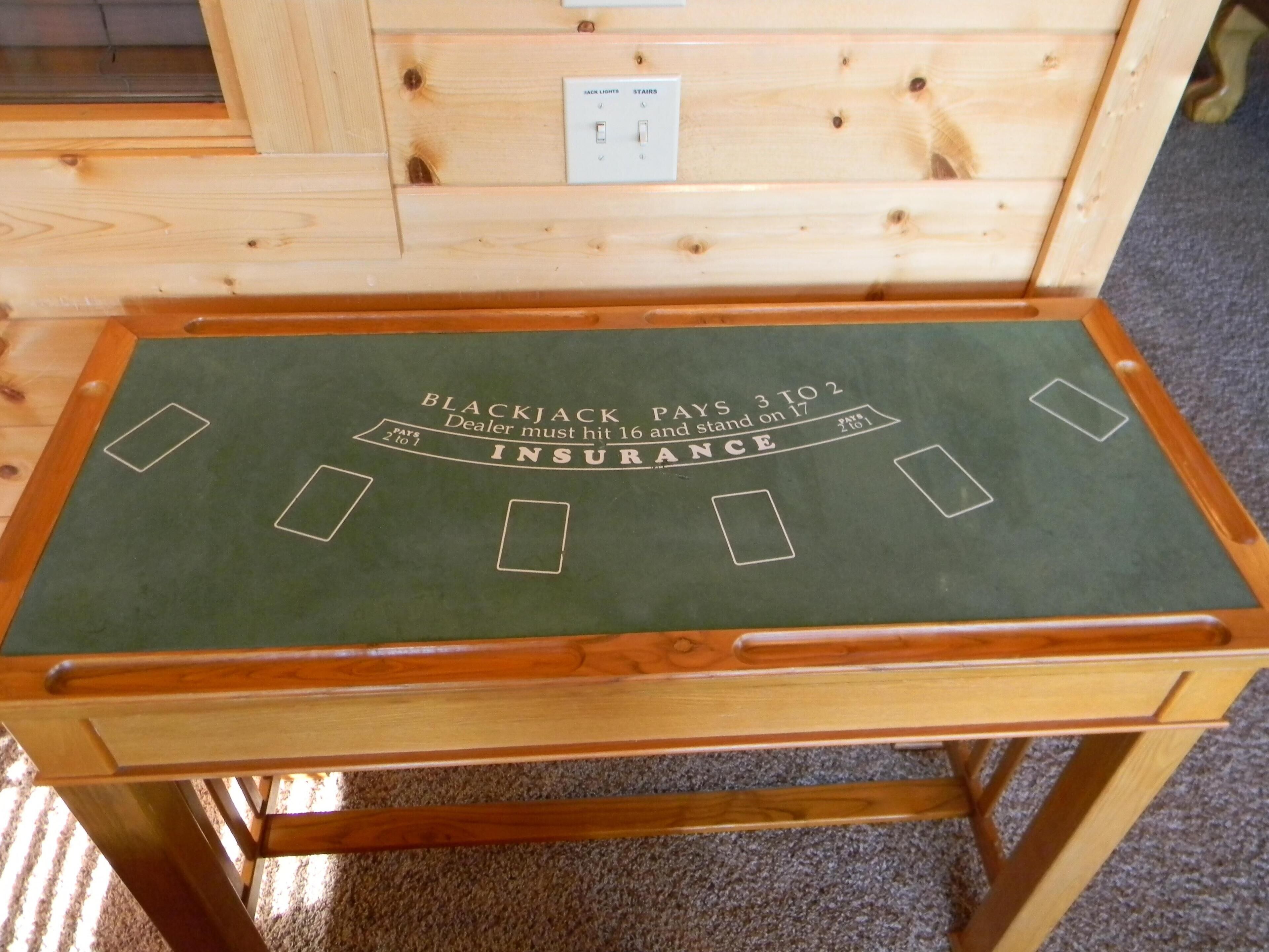 Una mesa de blackjack con fieltro verde y estructura de madera.