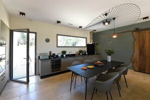 A modern kitchen with a dining area, a large window, and a ceiling fan.