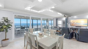 Una sala moderna con comedor, un televisor grande y vistas al océano.