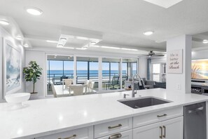A modern kitchen with a large island, white cabinetry, and a view of the ocean. - Beach, Sand, Sun! (Indian Rocks Beach)