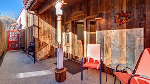 A wooden exterior with a red door, a bench, and a glass door leading inside.