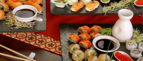 A variety of sushi dishes on a table with chopsticks and a small bowl of soy sauce.