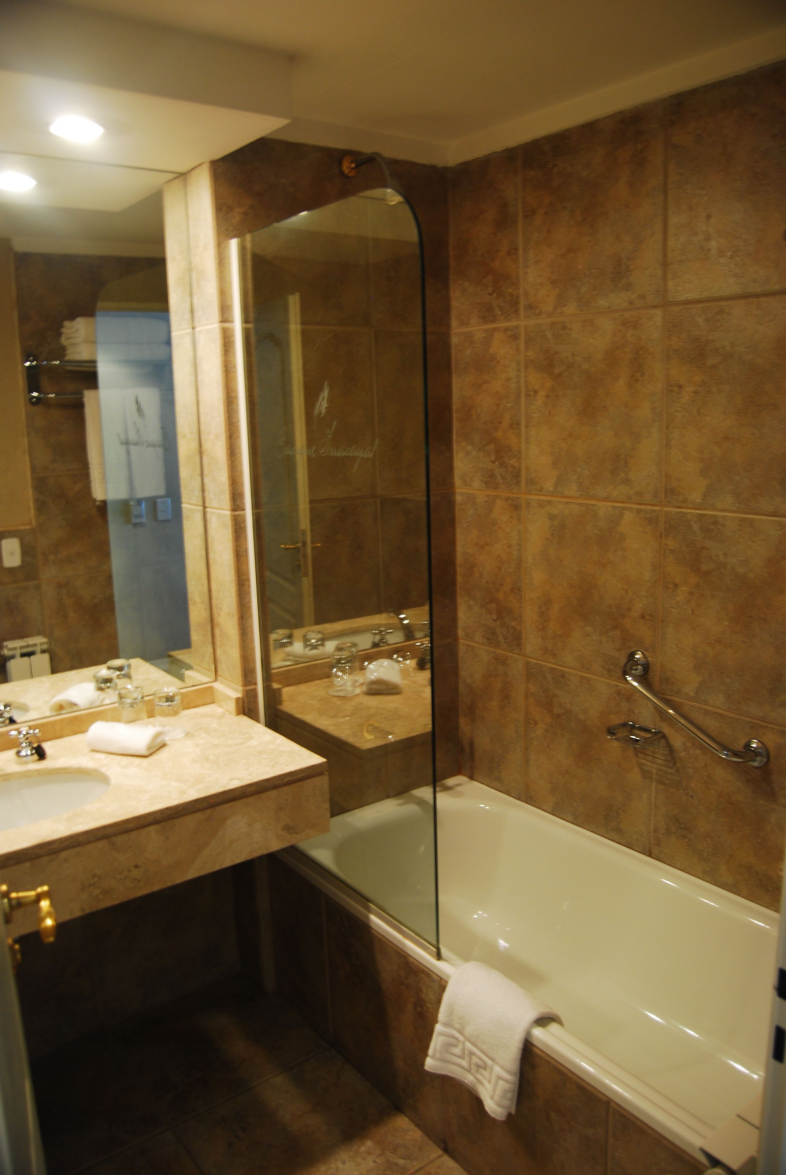 Un baño con bañera, ducha con cerramiento de vidrio y dos lavamanos con espejo.