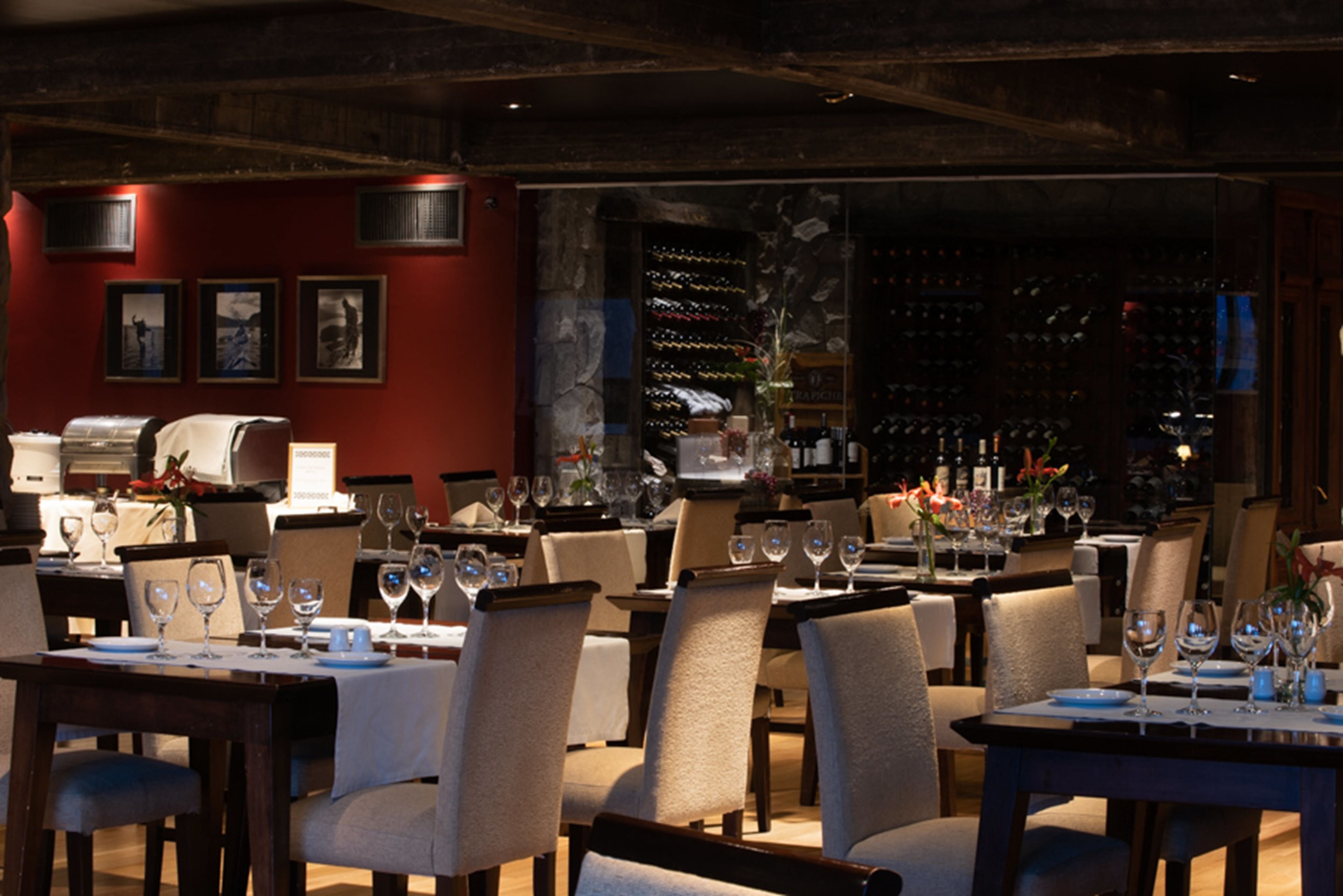 A restaurant with multiple tables set for dining, chairs, and wine glasses.