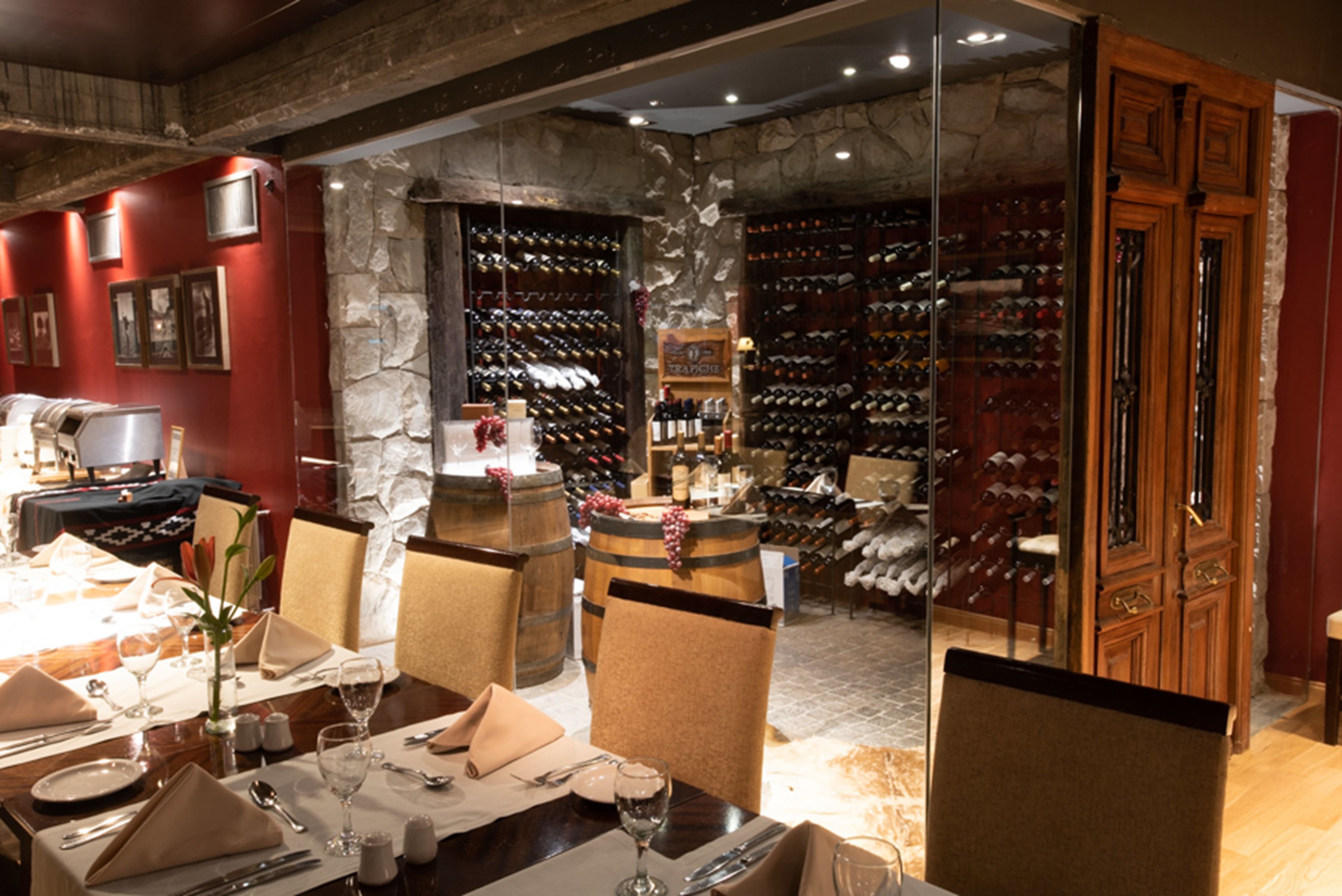 Un comedor con pared de piedra, estanterías para vinos y puerta de madera.