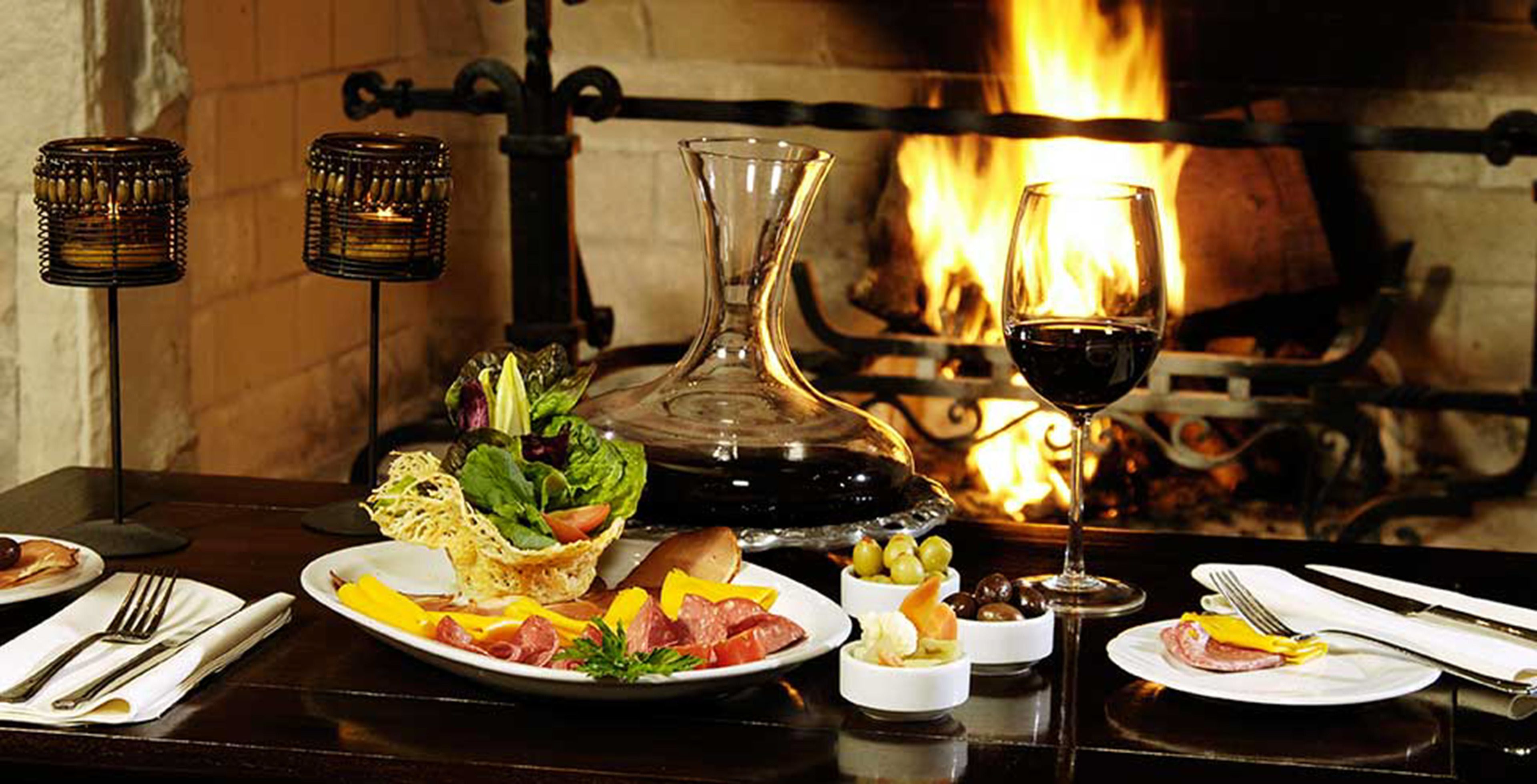 Une table à manger avec différents plats, un verre à vin et des chandeliers.