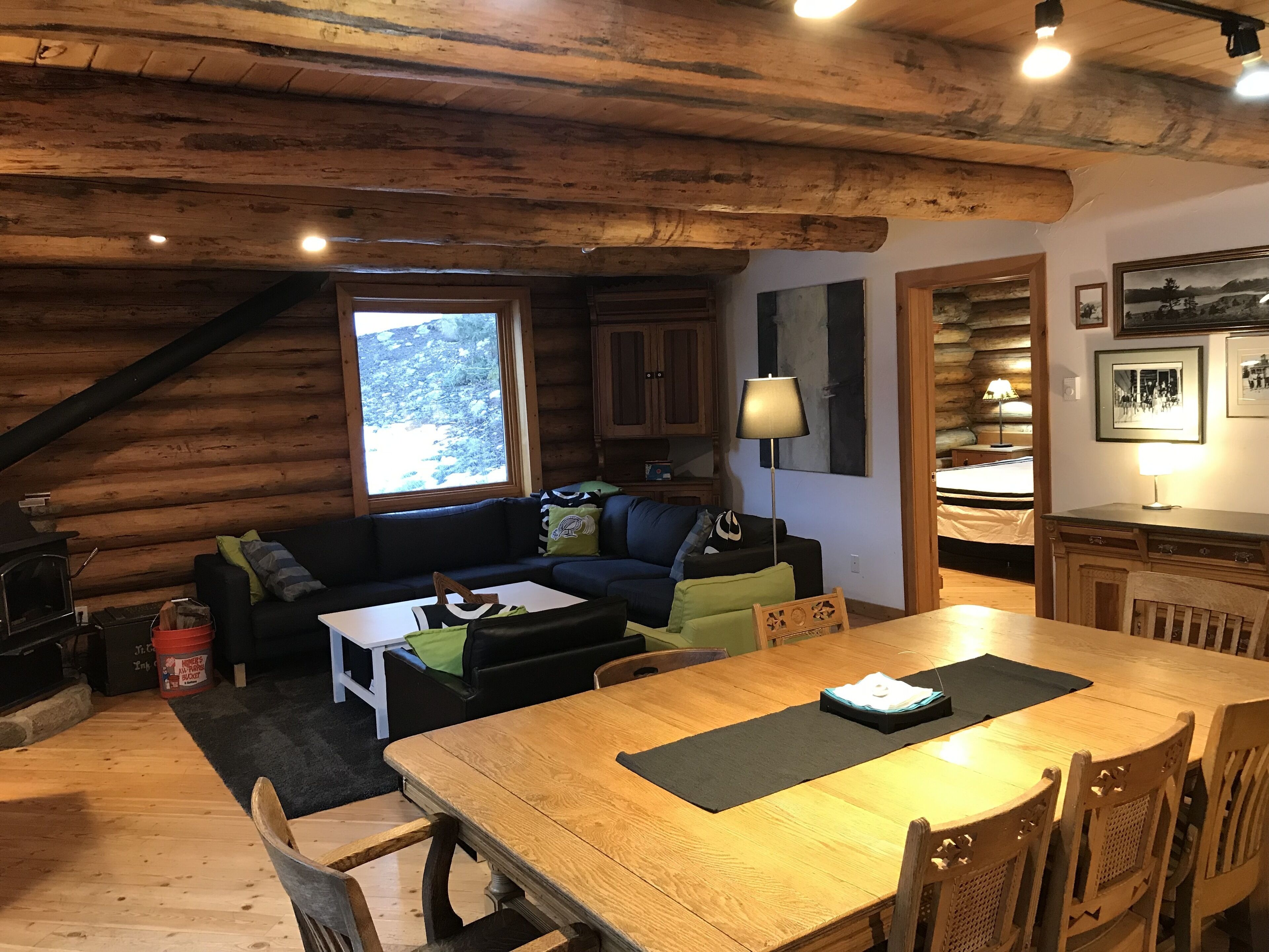 Een gezellig houten blokhutinterieur met een houten eettafel, een bank en een open haard.