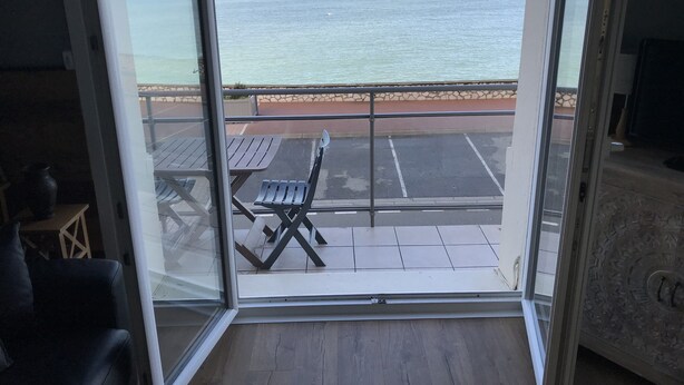A room with a view of the ocean through large glass doors.