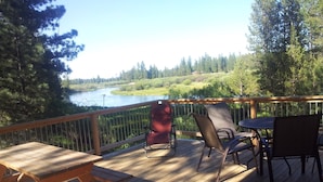 A wooden deck with a picnic table and chairs overlooking a river and forested area. - Log home On the Deschutes River Bend, OR (Bend)