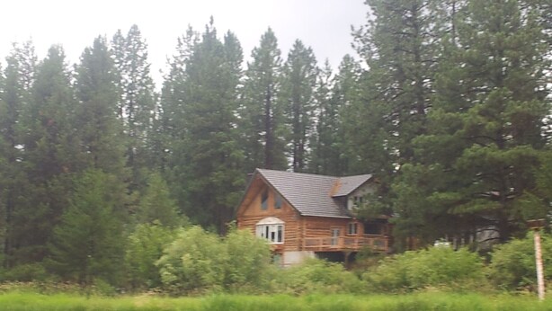 A cabin surrounded by dense forest and a calm lake. - Log home On the Deschutes River Bend, OR (Bend)