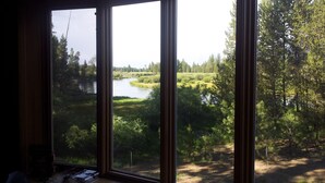 A room with large windows overlooking a forested area and a river. - Log home On the Deschutes River Bend, OR (Bend)