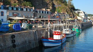En havn med fortøjede både, en restaurant ved vandet og bygninger langs kysten.