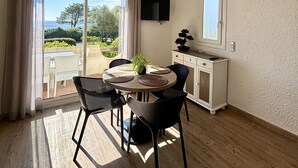 Un coin repas avec une table ronde, des chaises noires, une plante en pot et un luminaire suspendu au plafond.
