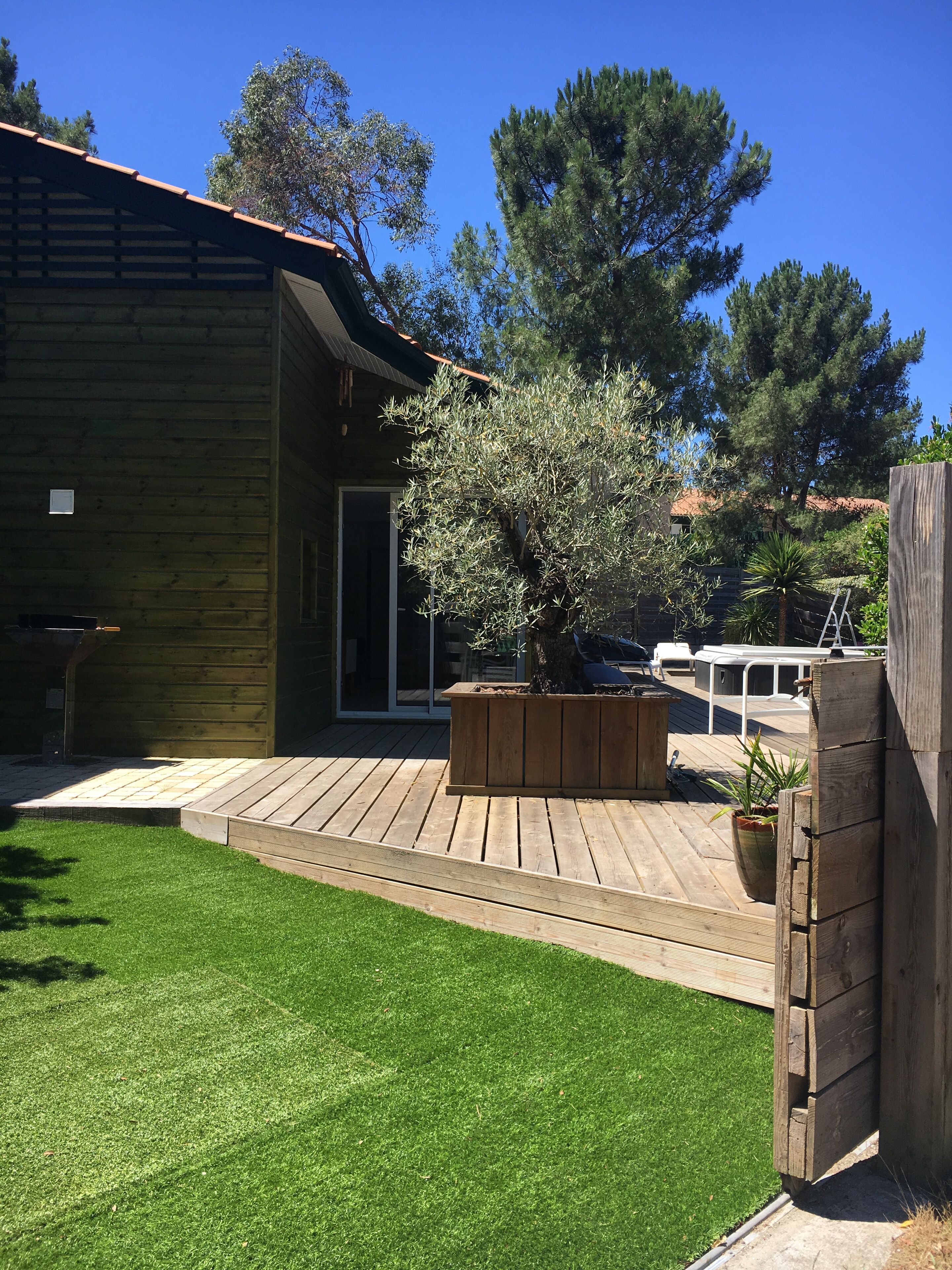 Une terrasse en bois avec un jardin intégré, une petite pelouse et une clôture en bois.
